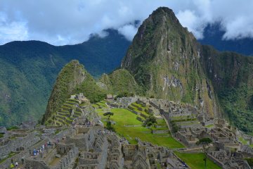 Panoramic view of the ancient Inca city of Machu Picchu, showcasing stone ruins, terraced fields, and Huayna Picchu mountain in the background.